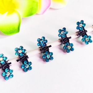 Détail de mini pinces à cheveux fleur avec strass bleus sur clips métalliques