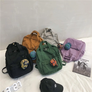 Minimalist canvas backpacks in five colors with cute checkered hat charms on white background