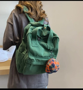 Rear view of model wearing a minimalist green canvas backpack with a cute small charm