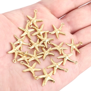 Golden starfish pendants held in hand to show size for jewelry making DIY accessories