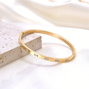 Elegant gold stainless steel hinged bangle featuring rectangular inlaid crystals on silk