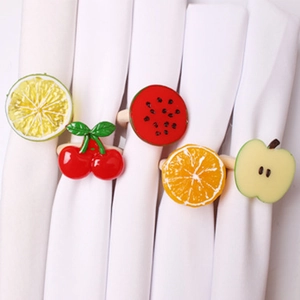 Detail of five fruit-shaped napkin rings including lemon, cherry, and watermelon designs