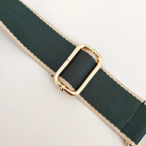 Close-up of dual-tone green and beige woven shoulder strap with gold metal buckle