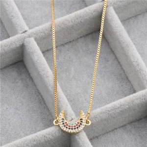 Macro view of gold crescent moon necklace with colorful zircon stones in a velvet tray