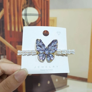 Detailed close-up of a golden butterfly hair clip with purple and clear zircon crystals