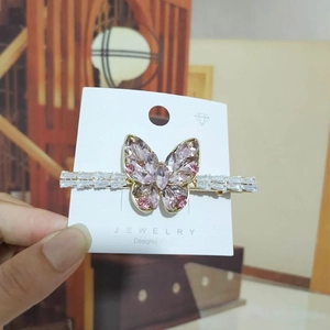 Detail of a gold butterfly hair clip with pink crystals and clear rhinestones
