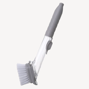 Long-handled kitchen dish brush with gray soap dispenser and white bristles on plain background