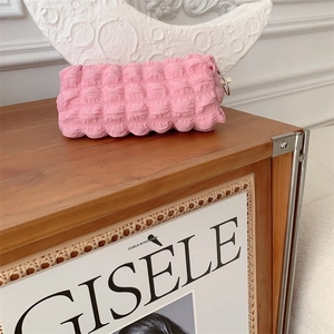 Close-up of pink bubble texture pencil case on a wooden desk with decorative objects