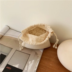 Minimalist cotton linen drawstring bag in off-white on a wooden table for storage