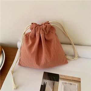 Close-up of brick red linen drawstring storage bag with dual-cord closure and textured fabric