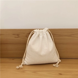 Close-up of minimalist cream cotton linen drawstring bag on a natural wooden table
