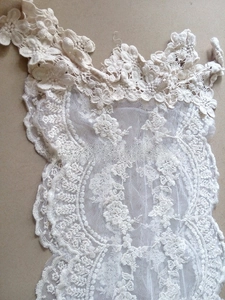 Detailed close-up of cream lace scarf with intricate 3D floral embroidery and scalloped edges