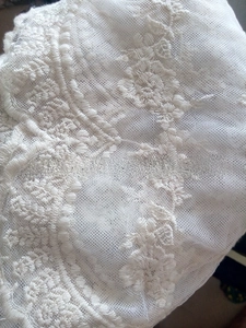 Detail of white lace scarf showing intricate 3D floral embroidery and mesh texture