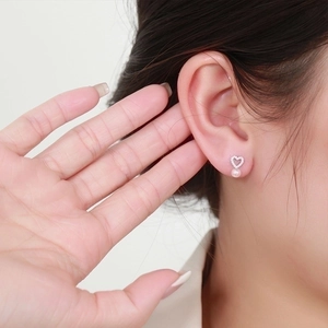 Elegant silver heart earrings with pearls and crystals shown on model's ear