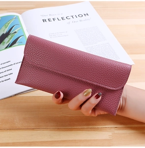 Close-up of litchi grain leather wallet in mauve being held over a wooden table