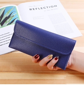 Detail view of deep blue leather wallet with litchi grain texture held by hand