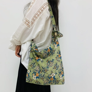 Floral corduroy shoulder bag with green pattern and side bow detail on white outfit