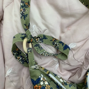Detailed shot of green corduroy floral bag featuring a wooden ring and silver zipper closure