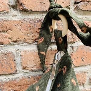 Close-up of green corduroy bag showing wooden ring connection and metal zipper detail