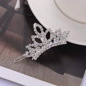 Elegant silver crown hair clip with sparkling clear and purple rhinestones on a magazine
