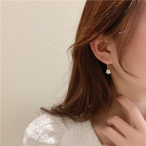 Elegant gold flower drop earrings with zircon crystals shown on a female model