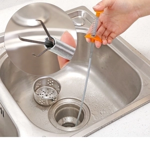 Close-up of flexible drain clog remover tool with four-claw metal gripper in kitchen sink