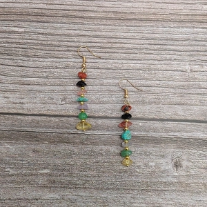 Detail of colorful stacked stone teardrop earrings with gold bead accents on wood