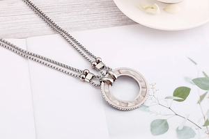 Detail of a double-layered silver necklace with a rhinestone-encrusted round pendant