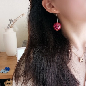 Detail of sweet cherry drop earrings with translucent dried flower texture and gold studs
