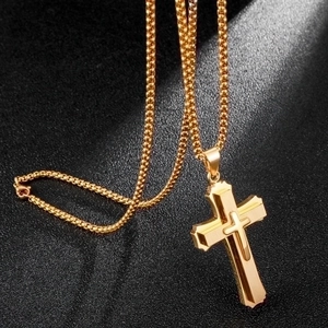Three-layer 3D gold stainless steel cross pendant necklace on dark textured background