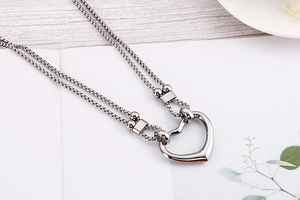 Detail of silver double layer heart necklace on white card with wooden texture background