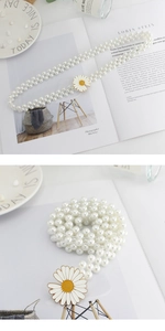 Détail d'une ceinture en perles avec fermoir métallique marguerite sur fond blanc minimaliste