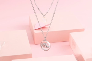 Double-layered silver stainless steel necklace with Mum pendant on a pink display setup