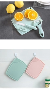 Close-up of ceramic fruit knife set with plastic cutting board and peeler in green and pink