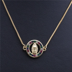 Gold Virgin Mary charm bracelet with colorful pavé stones on a black leather surface