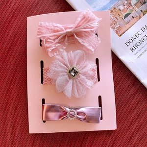 Three-piece set of pink lace hairbands and a purple bow clip on a display card