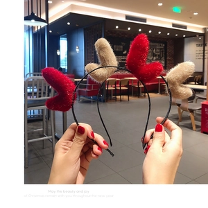 Close-up of plush red and camel heart-shaped Christmas headbands held in hand