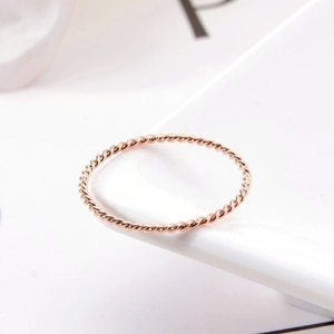 Minimalist twisted rope ring in rose gold finish shown on a white ceramic tray