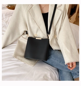 Detail of black minimalist bucket bag with gold hardware and matte leather texture