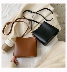 Chic brown and black matte leather bucket bags displayed with a coffee cup and jewelry