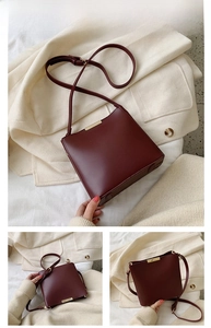 Detailed view of wine red leather bucket bag with gold metal trim and adjustable strap
