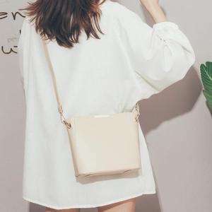 Chic beige bucket bag for women worn by a model in a minimalist and stylish setting