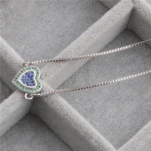 Gros plan d'un pendentif cœur avec oxydes de zirconium bleus et verts sur une chaîne