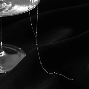 Dettaglio di collana con nappe d'argento e perline su elegante tessuto di seta nera