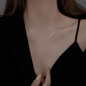 Collana minimalista con nappa lunga a forma di Y e perline d'argento indossata da un modello