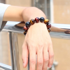 Natural multicolor tiger eye stone bracelet with lightning flash on a model's wrist