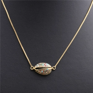 Detail of gold shell pendant with colorful cubic zirconia on black leather background