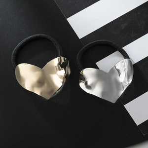 Golden and silver heart-shaped hair ties with textured metal finish on striped background