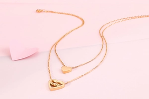 Detail of double-layer necklace with heart pendant and mom engraving in gold finish