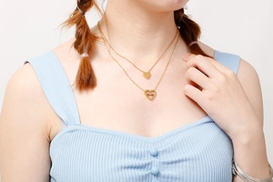 Close-up of golden double-layer heart necklace with MOM engraving on female model neck